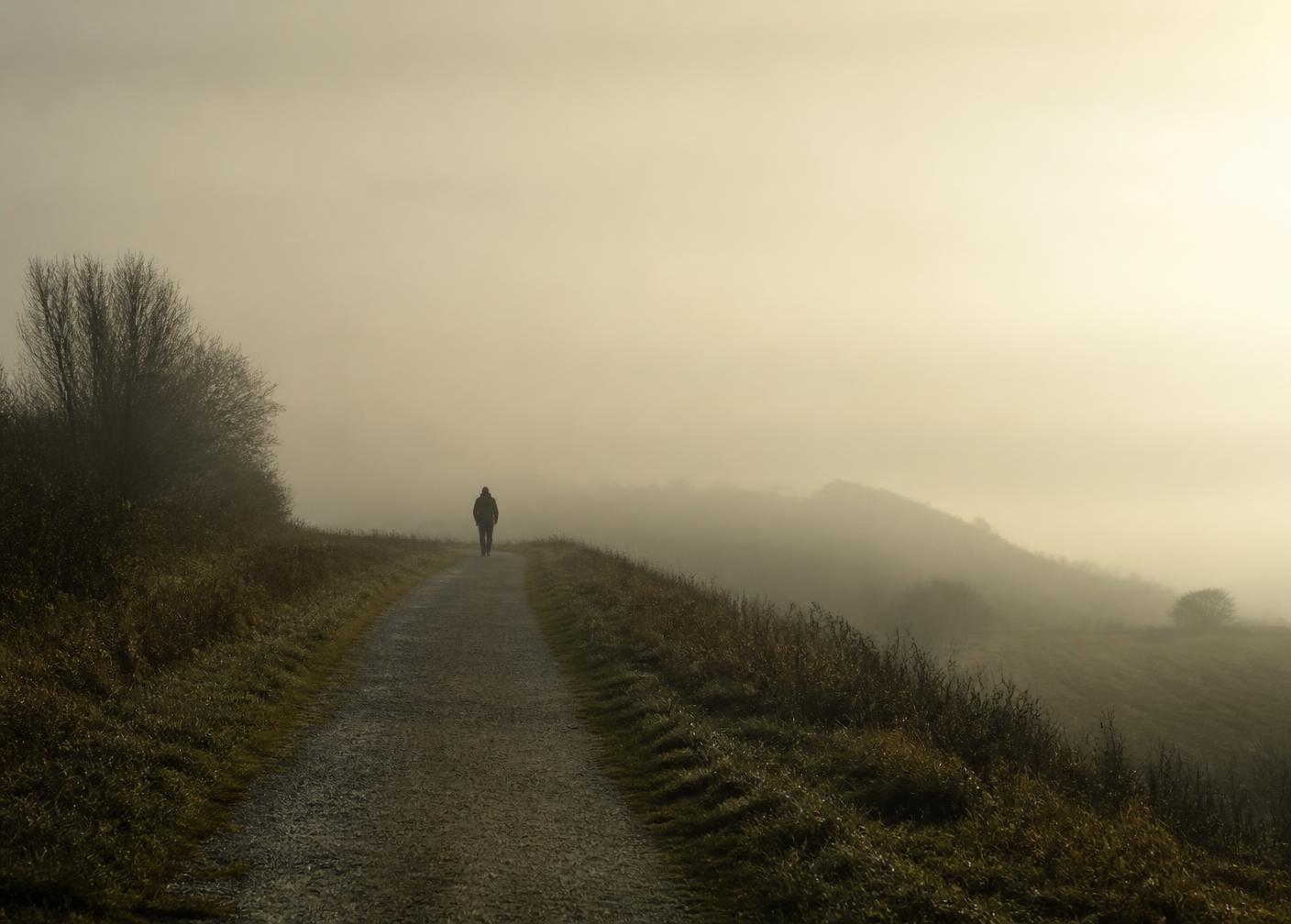 Silhueta distante de uma pessoa caminhando ao amanhecer